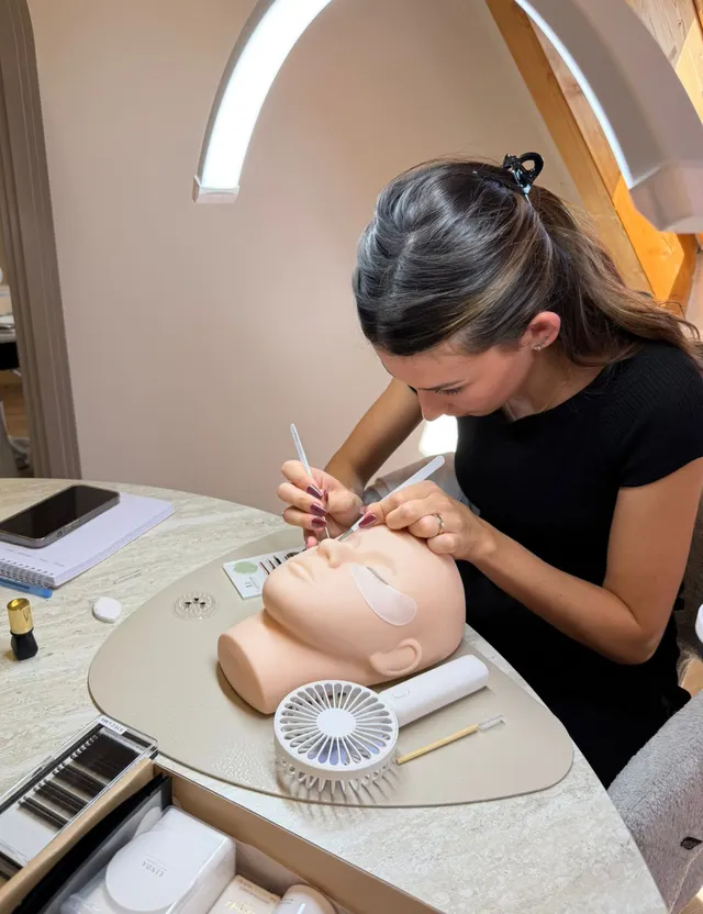 Teilnehmerin übt die Wimpernverlängerung am Übungskopf in der Linda Beauty Academy